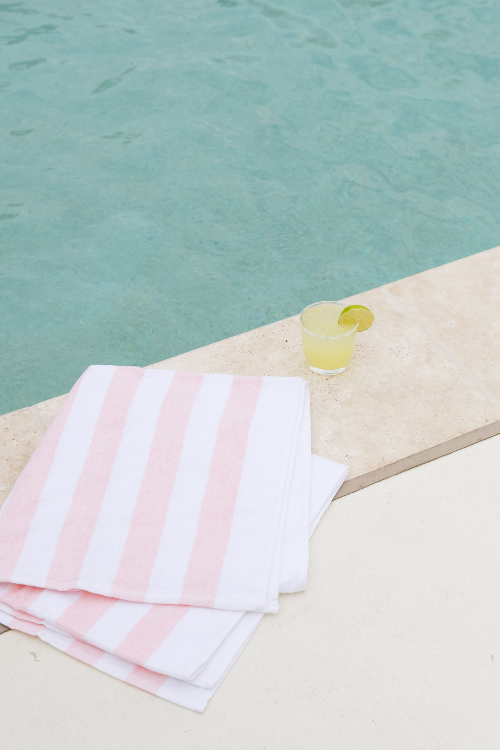 A beach towel and a yellow drink next to a pool at Salt Ranch hotel