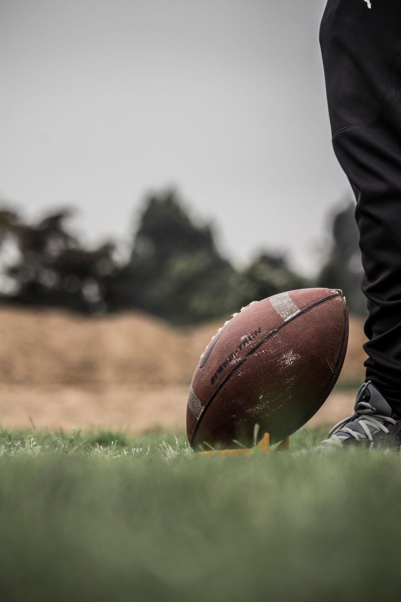 Football in grass with person's right leg.